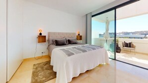A modern bedroom with a large bed, two bedside lamps, a view of the city through a glass door, and a balcony with outdoor furniture. - Elegant La Cala Escape: Relax in Style in this Luxury Townhouse (La Cala de Mijas)