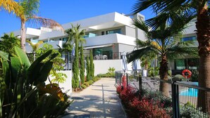 A modern building with a white facade, surrounded by tropical plants and a clear blue sky. - Elegant La Cala Escape: Relax in Style in this Luxury Townhouse (La Cala de Mijas)