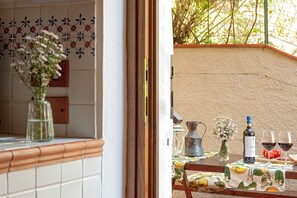 Un comedor con una mesa preparada para dos personas, que incluye una botella de vino, copas y un pequeño jarrón con flores.