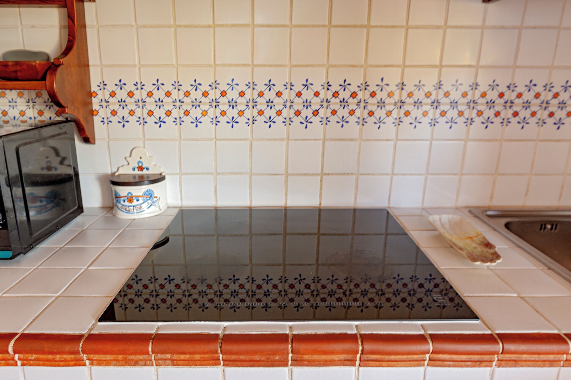 Une cuisine équipée d’une plaque de cuisson à induction noire, d’un four à micro-ondes et d’un évier.