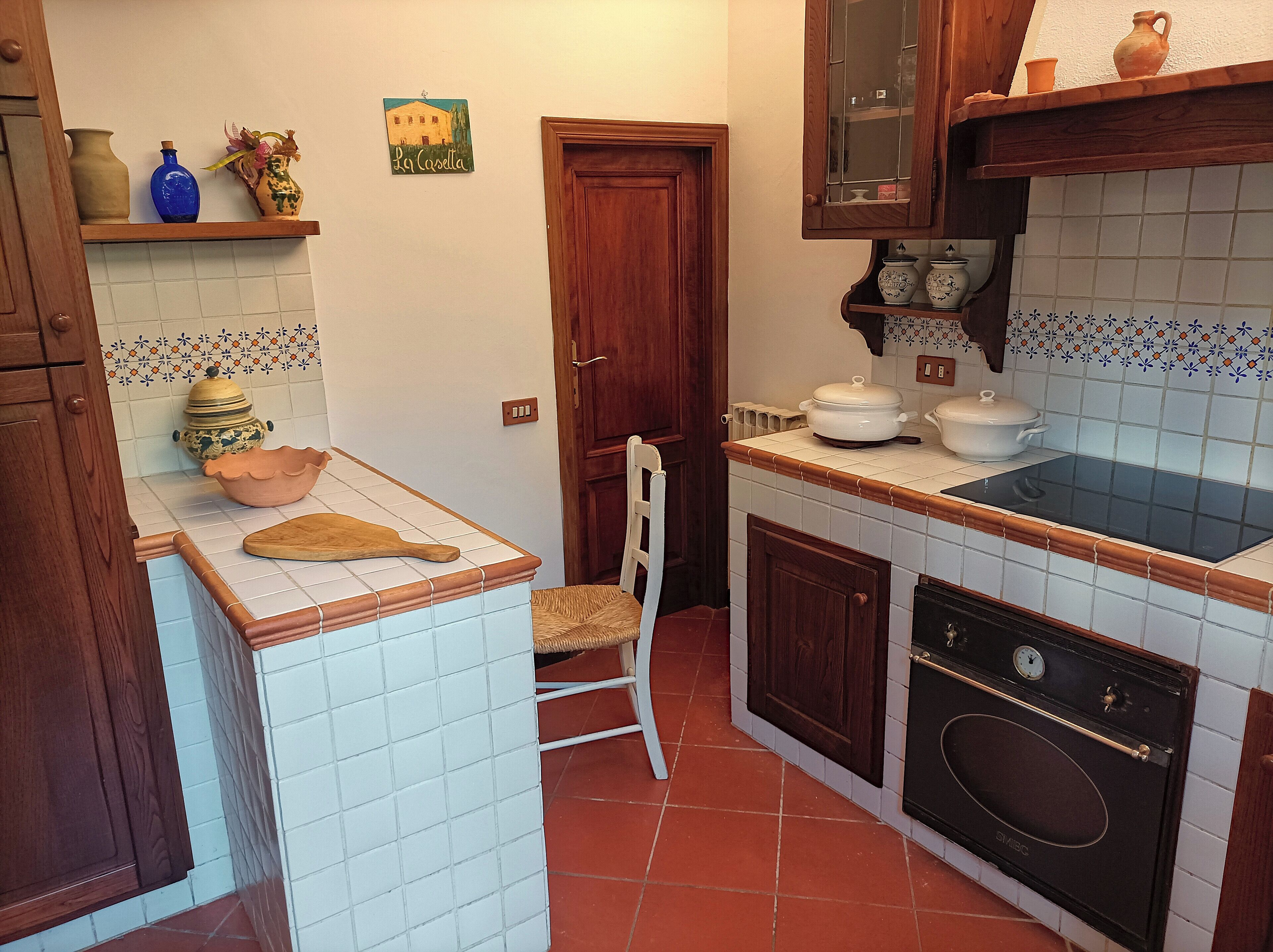 Une cuisine de taille réduite, avec des carreaux blancs, un plan de travail en bois, une cuisinière et une chaise.
