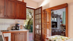 A kitchen with wooden cabinets, a coffee machine, and a window with a view of greenery. - VILLA CAMELIA TUSCANY villa with pool surrounded by olive trees - wonderful view (Pescia)