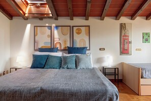 Un dormitorio con una cama grande, una mesita de noche, un escritorio y una silla. Hay obras de arte en la pared y un cuadro de una cabina telefónica roja.