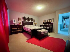 Une chambre à coucher avec un lit, une commode, une table de chevet et un tapis rouge.