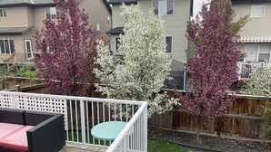 A deck with outdoor furniture, a wooden fence, and houses in the background. - Fully furnished elegant suburban house with desirable amenities and location. (Calgary)