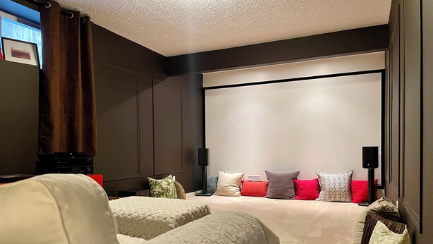 A modern bedroom with a large bed, a seating area with a sofa, and a flat-screen TV mounted on the wall. - Fully furnished elegant suburban house with desirable amenities and location. (Calgary)