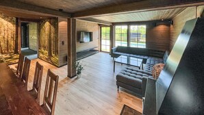 A spacious living area with a fireplace, a sofa, and a dining area with chairs.