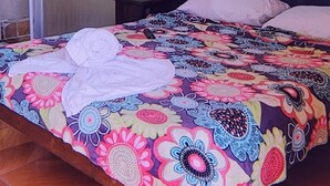A room with a bed, a wooden ceiling, a 'No Smoking' sign, and a partially open door. - Alpha Arenal - Hostel (La Fortuna)