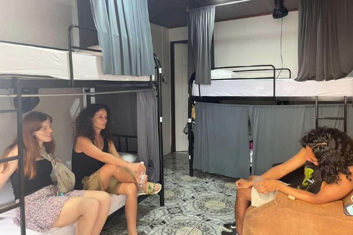 Un dormitorio con literas, piso de baldosas y cortinas.