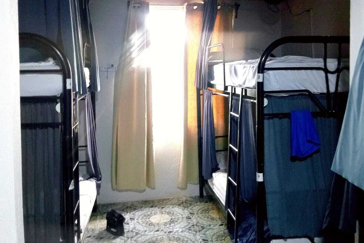 Un pasillo estrecho con literas a ambos lados, suelo de baldosas y una única fuente de luz al final.