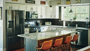Uma cozinha moderna com armários brancos, eletrodomésticos de aço inoxidável e uma ilha grande com banquetas.
