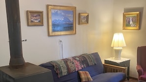 Una sala de estar acogedora con un sofá, una butaca, una mesa, una lámpara y una chimenea.