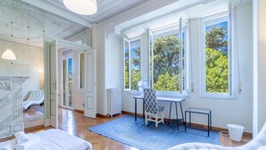 A bright room with a bed, a desk, and a chair near large windows. - 4 bedroom stunning apartment in Genova (Genova)