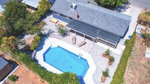 Uma casa moderna com piscina, painéis solares e varanda coberta.