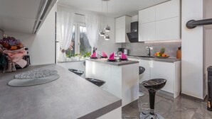 A modern kitchen with white cabinetry, a central island with pink napkins, and a bar stool.