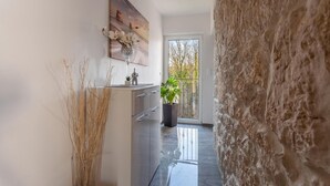 A modern kitchen with a large window, a stone wall, and a view of trees.
