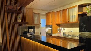 A modern kitchen with wooden cabinetry, a black countertop, and stainless steel appliances. - 3 bedrooms Family apartment (محافظة القاهرة‬)