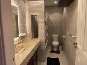 Une petite salle de bain comprenant un lavabo, un miroir, des toilettes et un espace douche.