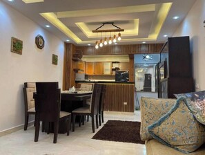 Une cuisine moderne avec des meubles en bois, un coin repas comprenant une table et des chaises, et un canapé agrémenté de coussins à motifs.