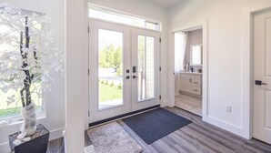 A bright hallway with a large window, a potted plant, and a door leading to a bathroom. - Luxury oasis in the woods, less than five minutes from the beach! (Wiarton)