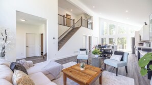 A spacious living room with a wooden coffee table, a sofa with patterned cushions, and a staircase leading to an upper level. - Luxury oasis in the woods, less than five minutes from the beach! (Wiarton)