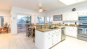 Una cocina moderna con gabinetes blancos, encimeras de granito y electrodomésticos de acero inoxidable.
