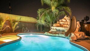 Una piscina con una formación rocosa y palmeras.