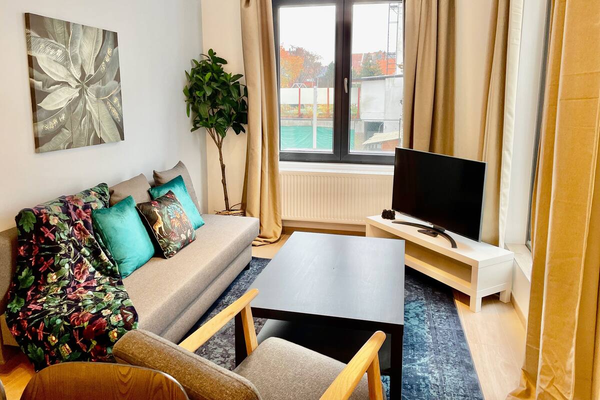 Ein modernes Wohnzimmer mit einer Couch, einem Fernseher und einem Couchtisch.