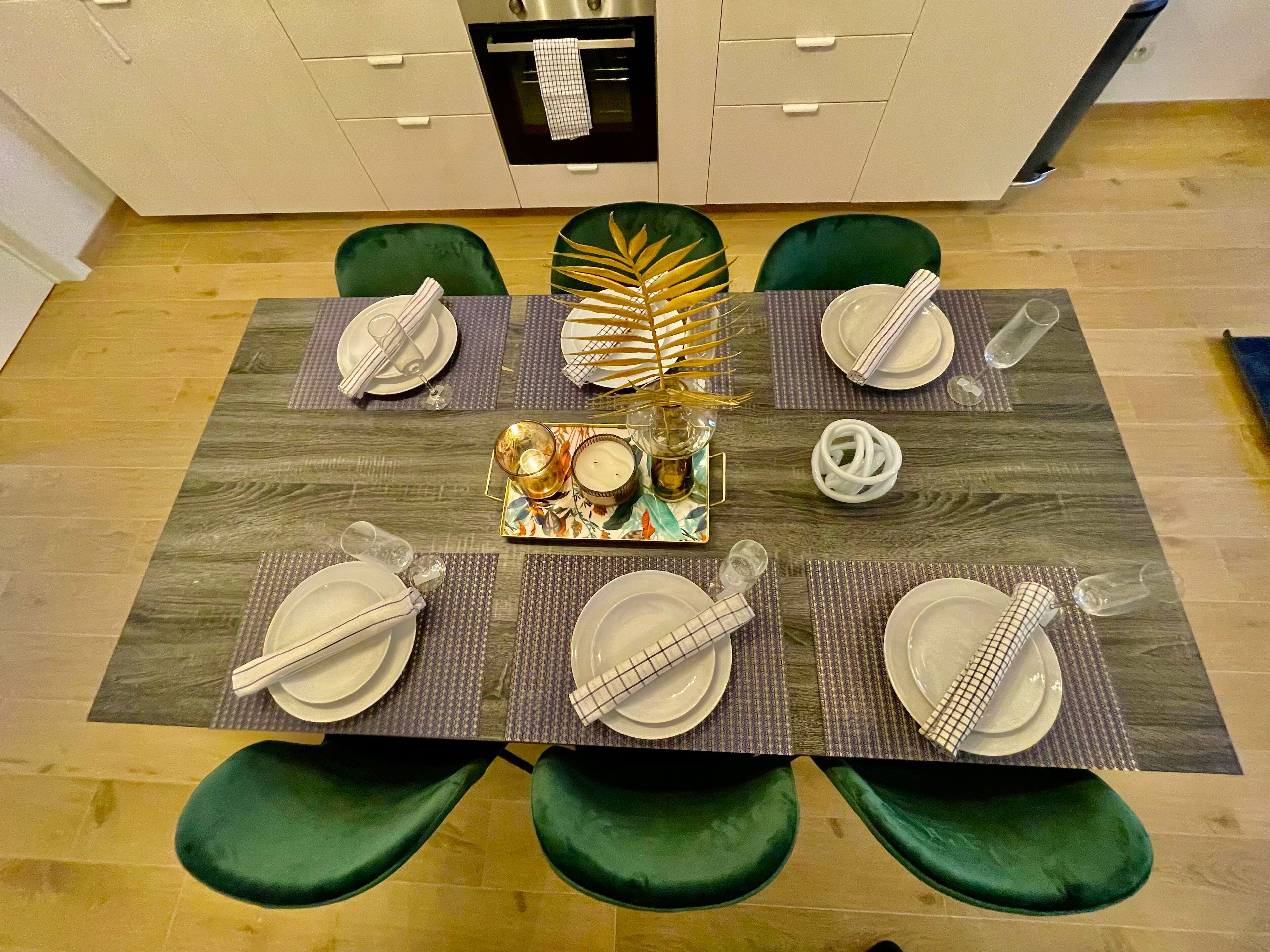 Et spisebord dækket med tallerkener, bestik og en midtpunktdekoration.