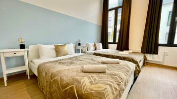 Une chambre d’hôtel avec deux lits, une table de chevet, une lampe et une fenêtre avec des rideaux.