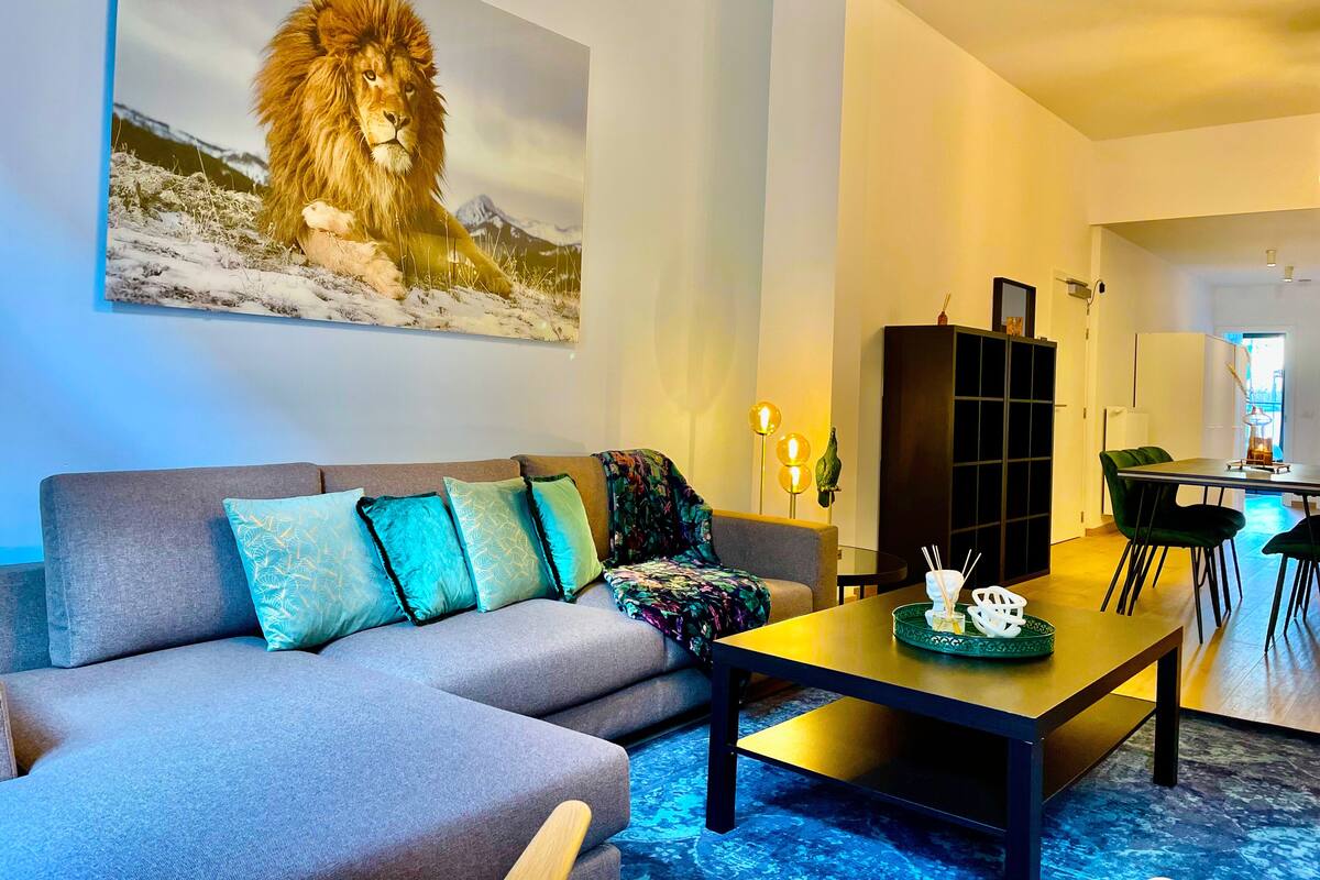 Ein modernes Wohnzimmer mit einem grauen Sofa, einem Couchtisch und einem Gemälde eines Löwen.