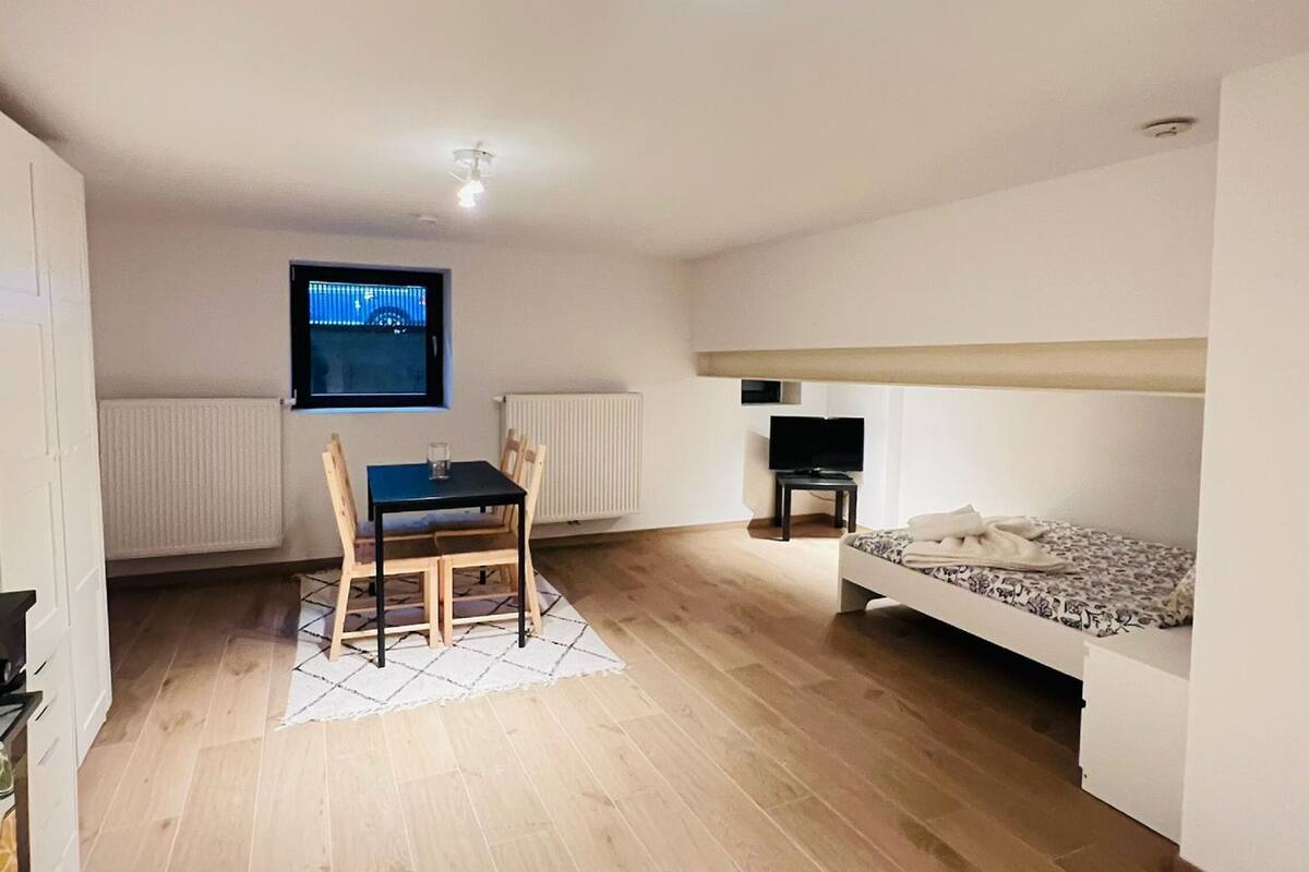Ein modernes Wohnzimmer mit Essbereich, einem an der Wand montierten Flachbildfernseher und einem Sofa mit gemustertem Bezug.