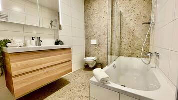 Un baño moderno con tocador de madera, ducha con cerramiento de vidrio y un inodoro blanco.