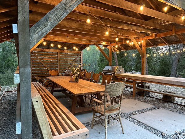 Relax under the pergola's shaded area, where a long table and comfortable seating invite dining and socializing.