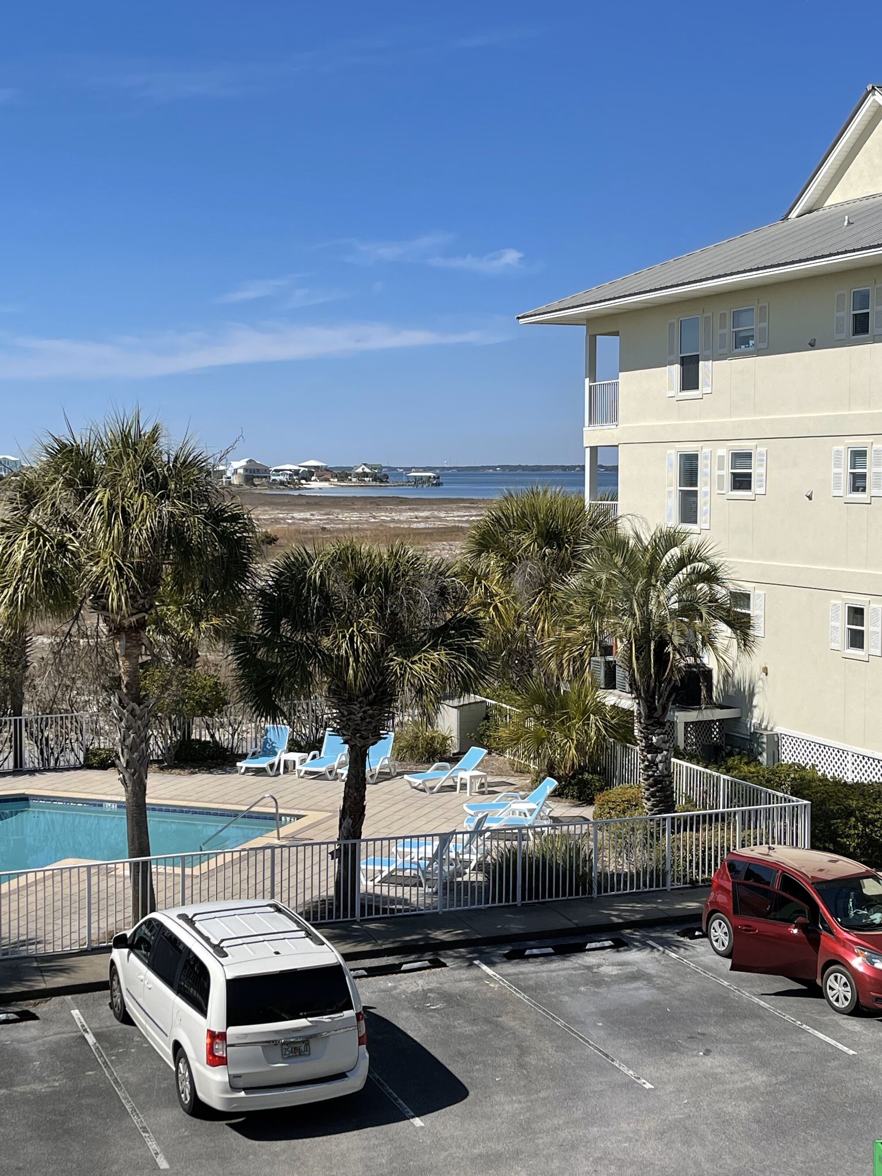 A parking lot with a swimming pool, lounge chairs, and a view of the ocean.