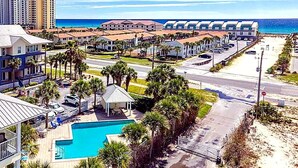 Un complexe hôtelier doté d’une piscine, de palmiers et offrant une vue sur la plage.