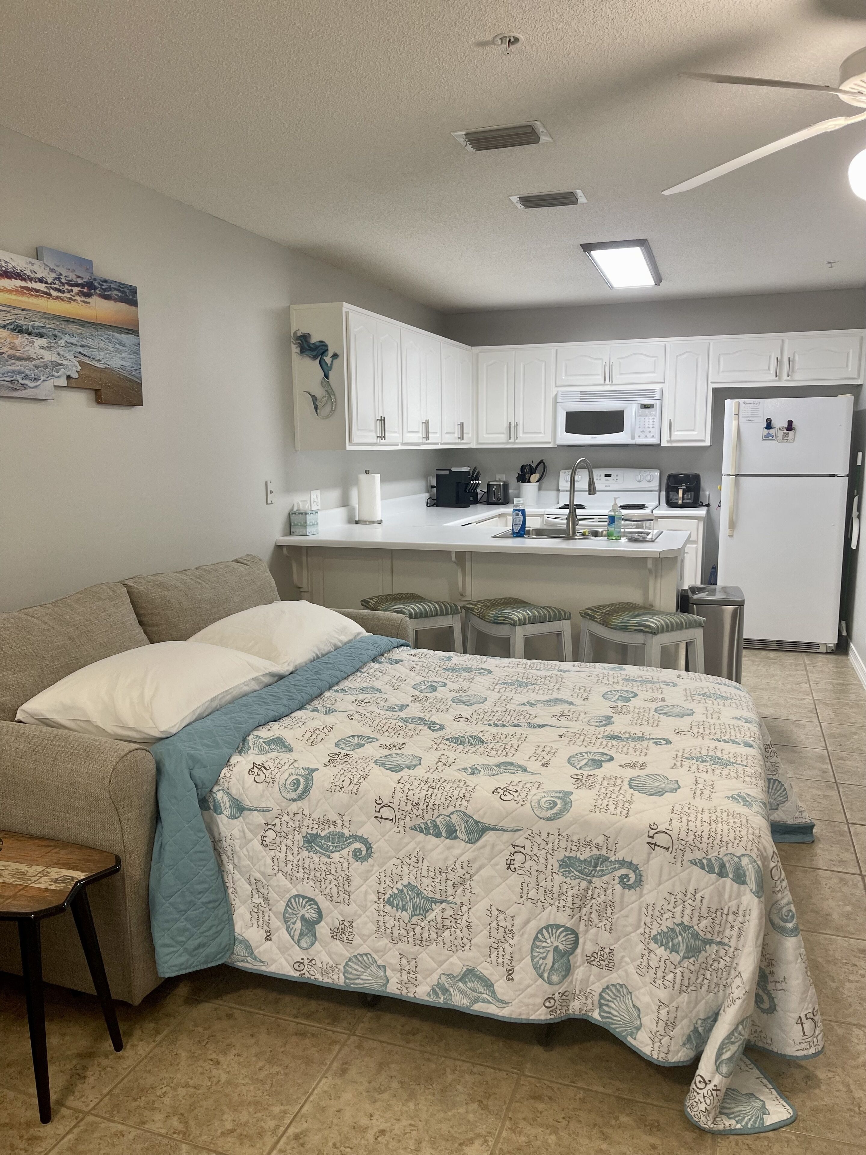 Un dormitorio compacto con cama, kitchenette pequeña y baño.