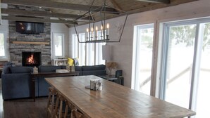 A spacious kitchen with a long wooden table, built-in seating, and a stone fireplace. - Adirondack Lakefront Getaway-Newly renovated, fireplace, gameroom, close to Gore (Wells)