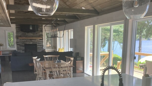 A modern kitchen with a white countertop, a black faucet, and a large window overlooking a lake. - Adirondack Lakefront Getaway-Newly renovated, fireplace, gameroom, close to Gore (Wells)