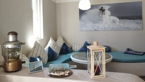 A cozy room with a view of the sea, featuring a round table, a ship in a bottle, and a lantern. - "Haus Seegang" approx. 100 sqm, close to the beach and with a large garden (Neubukow)