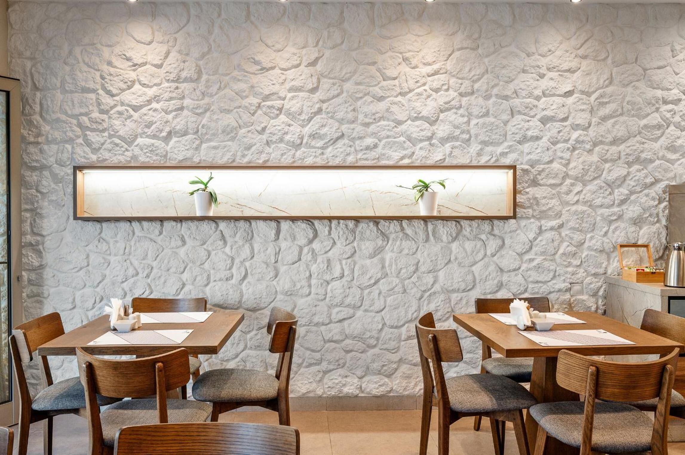 A dining area with stone wall decor, wooden tables, and chairs.