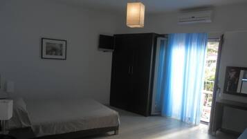 A bedroom with a bed, a wardrobe, a television, and a window with curtains.