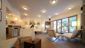 A modern living room with a sofa, two lounge chairs, a coffee table, and a TV.