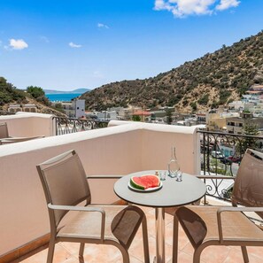 A balcony with a table, chairs, a bottle, and a slice of watermelon. - Glaros Hotel (Agios Vasileios)