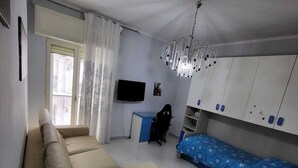 A compact living space with a sofa, a TV, a desk, and storage cabinets. - Apartment 3 min from the Museum (Napoli)
