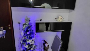 A room with a black entertainment unit, a small Christmas tree with lights, and a gnome decoration. - Apartment 3 min from the Museum (Napoli)