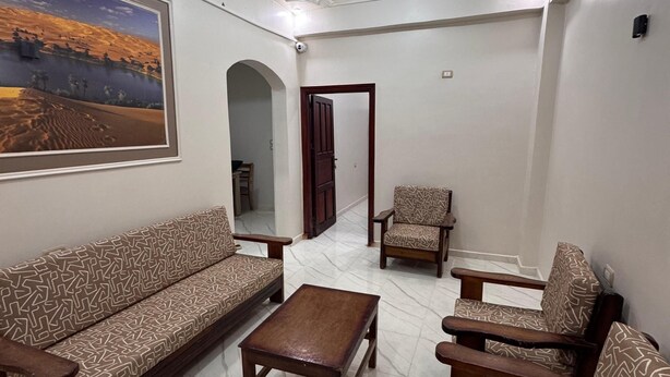 A living room with a sofa set, a coffee table, and a patterned rug. - Al-Manara Hostel Siwa Oasis (Siwa)