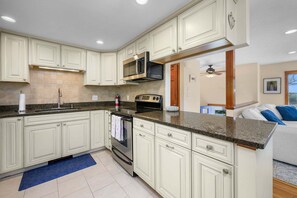 A kitchen with white cabinetry, a microwave, stove, and oven.