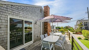 Une terrasse avec des sièges, une cheminée en briques et une grande porte-fenêtre coulissante.
