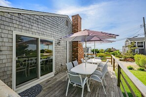 Eine Terrasse mit Sitzgelegenheiten im Freien, einem Ziegelkamin und einer großen Schiebeglastür.